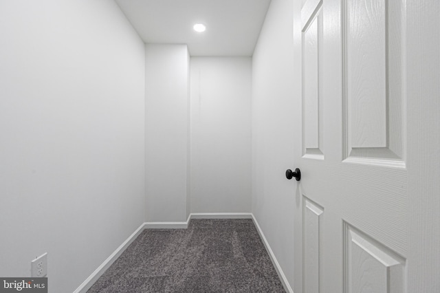 corridor featuring baseboards and dark carpet