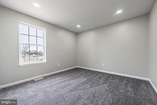 empty room with dark colored carpet, recessed lighting, visible vents, and baseboards