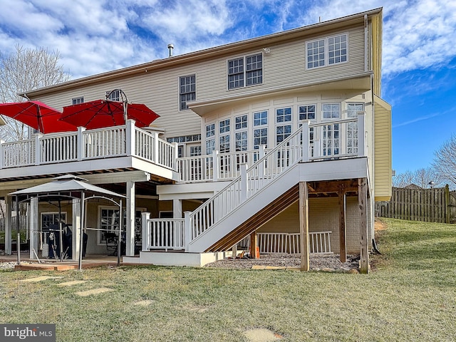 rear view of property featuring a deck, fence, stairway, and a lawn