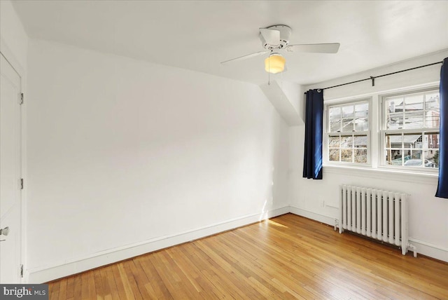 interior space featuring light wood-style floors, radiator, baseboards, and a ceiling fan