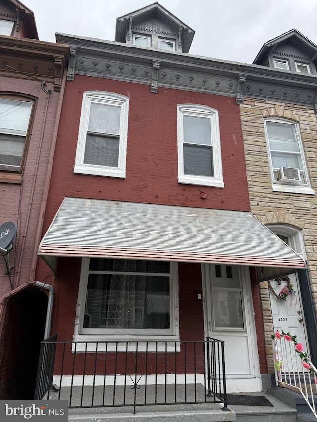 view of front facade featuring cooling unit, covered porch, and brick siding