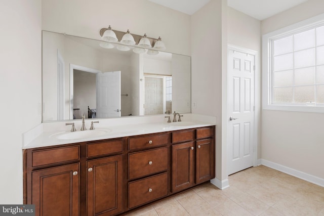 bathroom featuring double vanity, tile patterned flooring, baseboards, and a sink