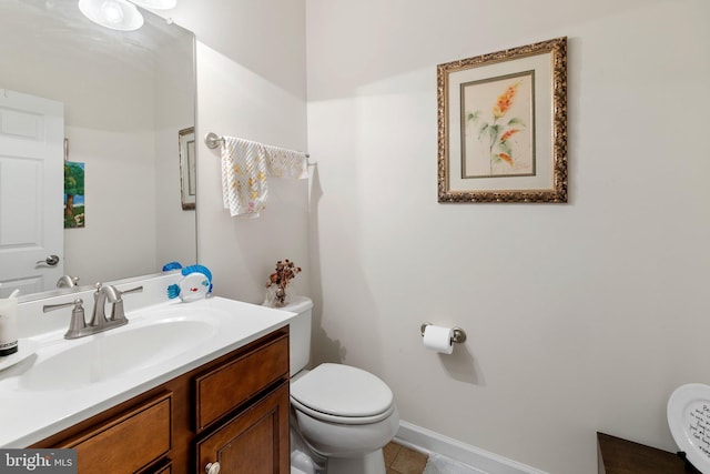 bathroom with tile patterned flooring, vanity, toilet, and baseboards