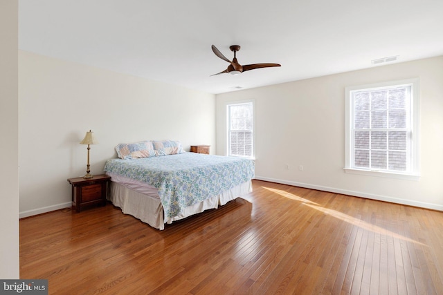 bedroom featuring ceiling fan, wood finished floors, visible vents, and baseboards