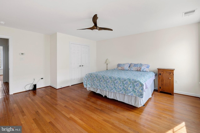 bedroom featuring a closet, visible vents, a ceiling fan, wood finished floors, and baseboards