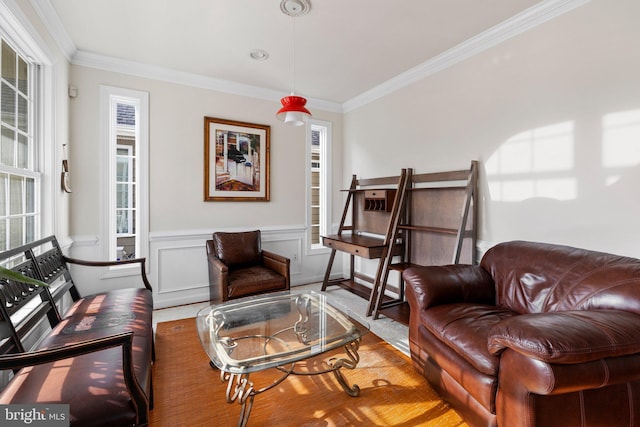 living area featuring a wainscoted wall, ornamental molding, and a decorative wall