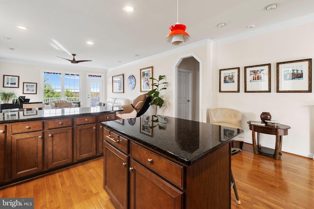 kitchen with a breakfast bar, crown molding, light wood-style flooring, open floor plan, and a kitchen island