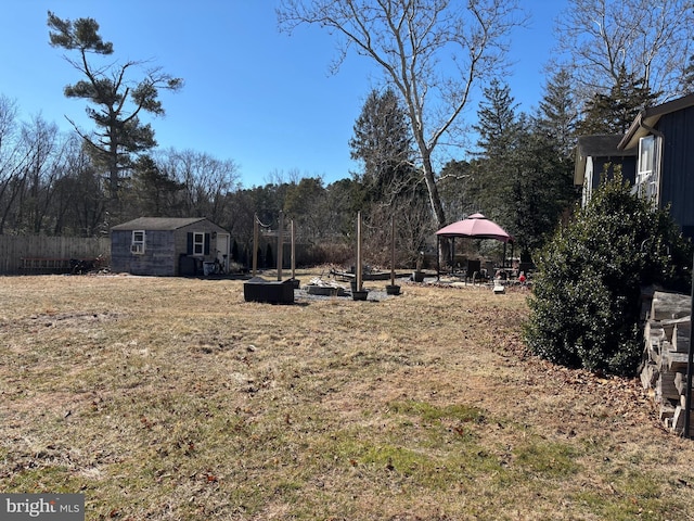 view of yard with an outbuilding, fence, a gazebo, and a storage unit