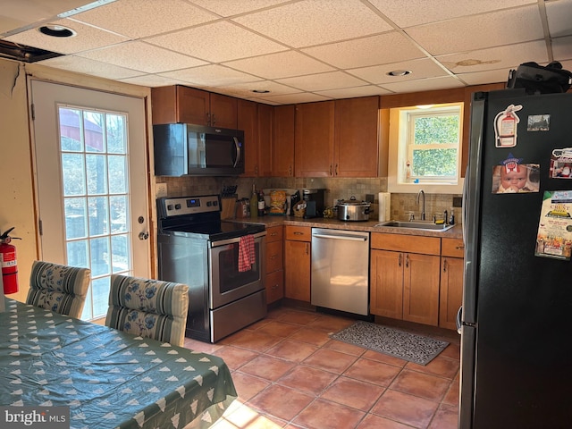 kitchen featuring appliances with stainless steel finishes, brown cabinetry, a sink, and tasteful backsplash