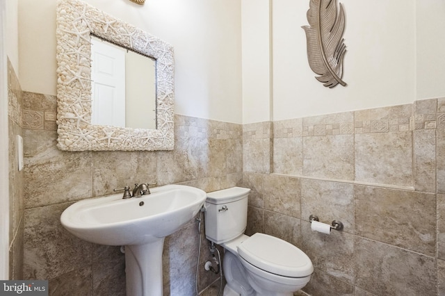 bathroom featuring a wainscoted wall, tile walls, and toilet