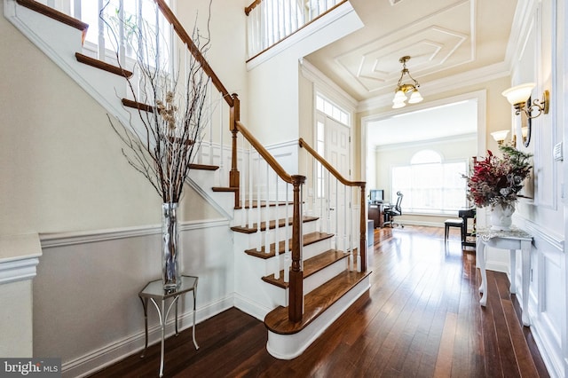 entrance foyer featuring dark wood-type flooring, crown molding, stairway, and a high ceiling