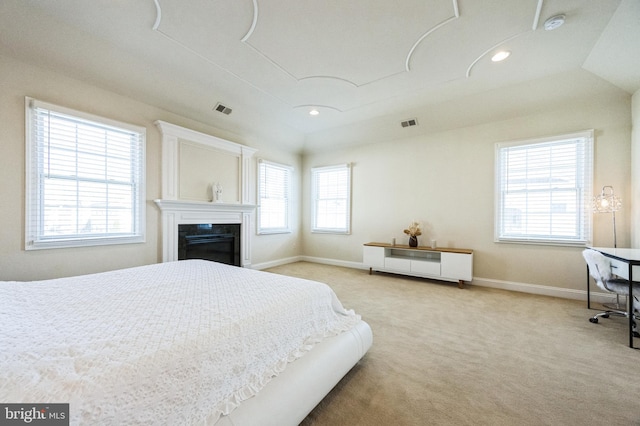 bedroom with recessed lighting, light colored carpet, visible vents, baseboards, and a glass covered fireplace