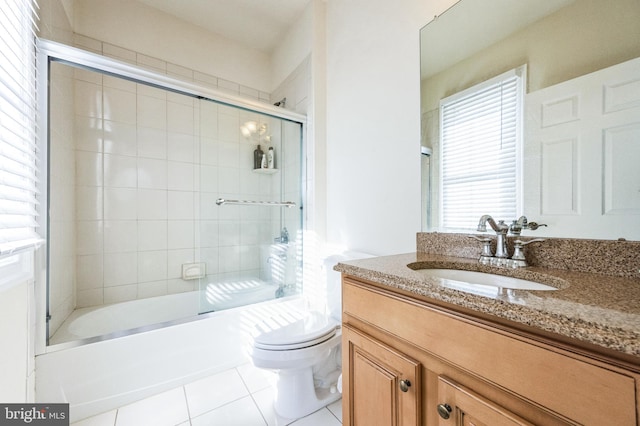 full bath featuring vanity, bath / shower combo with glass door, tile patterned flooring, and toilet