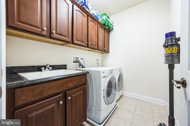 laundry area with light tile patterned floors, cabinet space, a sink, separate washer and dryer, and baseboards