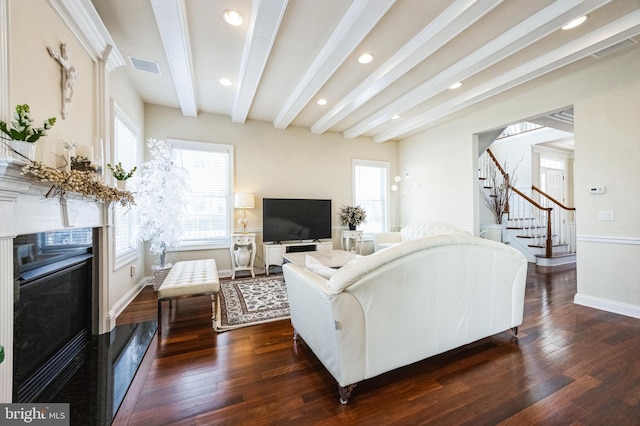 living area featuring stairs, visible vents, dark wood finished floors, and beam ceiling