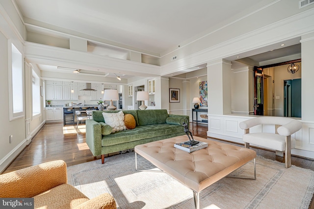 living room featuring light wood finished floors, visible vents, and a decorative wall