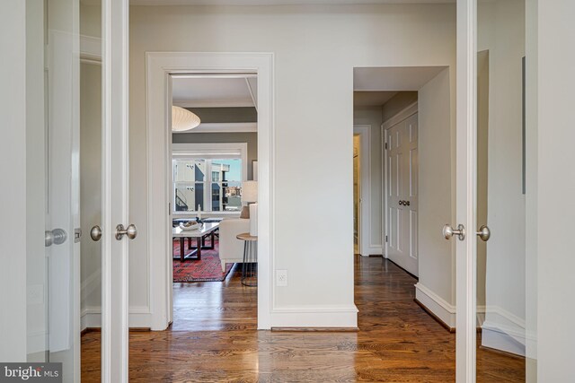 hallway with ornamental molding, baseboards, and wood finished floors