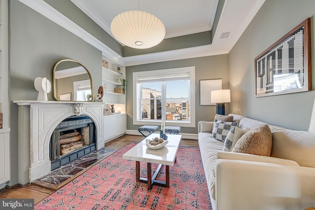 living room with a raised ceiling, crown molding, and wood finished floors