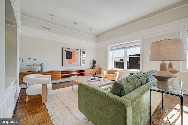 living room featuring visible vents, wood finished floors, and ornamental molding