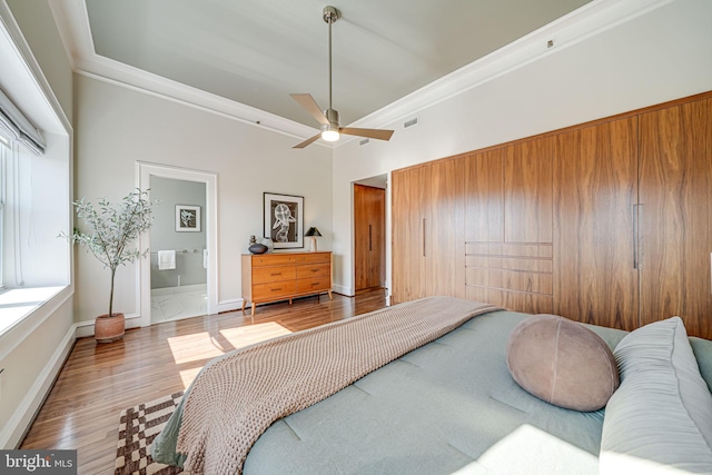 bedroom featuring visible vents, baseboards, connected bathroom, wood finished floors, and crown molding