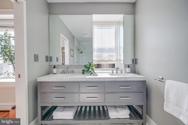 full bath featuring a shower stall, double vanity, a sink, and a healthy amount of sunlight