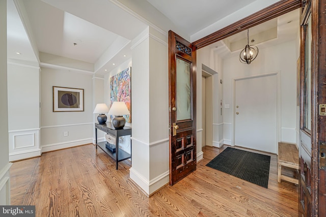 entrance foyer with a raised ceiling, baseboards, an inviting chandelier, and wood finished floors