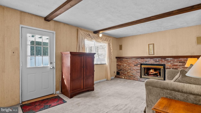 living area with a textured ceiling, light colored carpet, a fireplace, baseboards, and beam ceiling