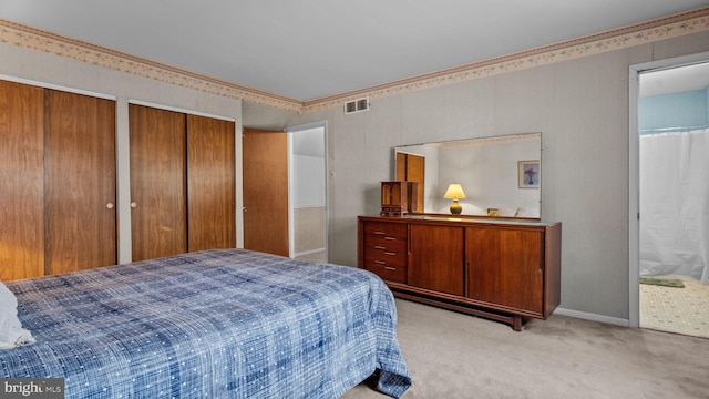 bedroom featuring two closets, light colored carpet, visible vents, connected bathroom, and baseboards