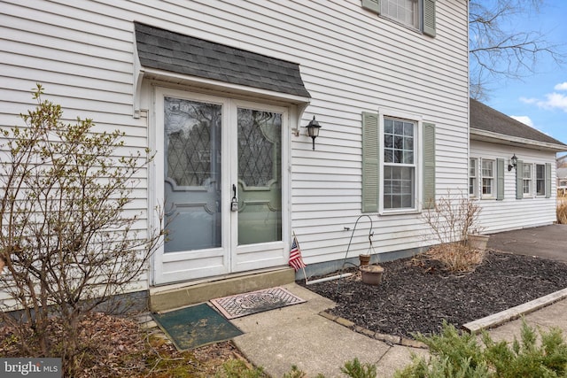 doorway to property featuring a shingled roof