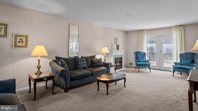 living area with a warm lit fireplace, baseboards, light colored carpet, and french doors