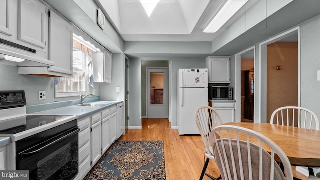 kitchen with freestanding refrigerator, light countertops, black range with electric cooktop, white cabinetry, and a sink