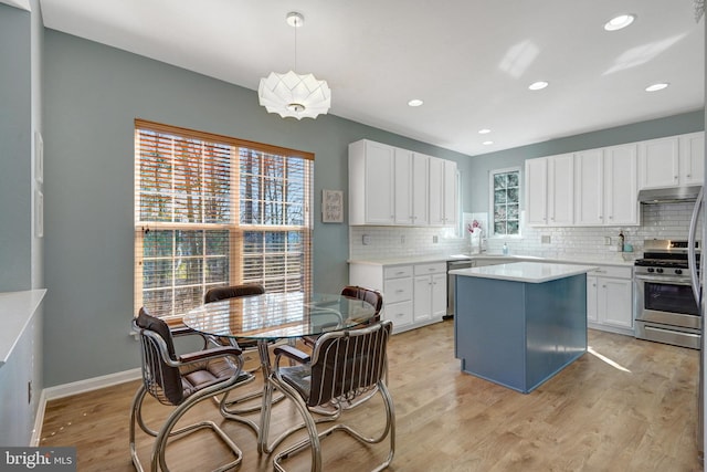 kitchen with appliances with stainless steel finishes, light countertops, decorative light fixtures, and white cabinetry