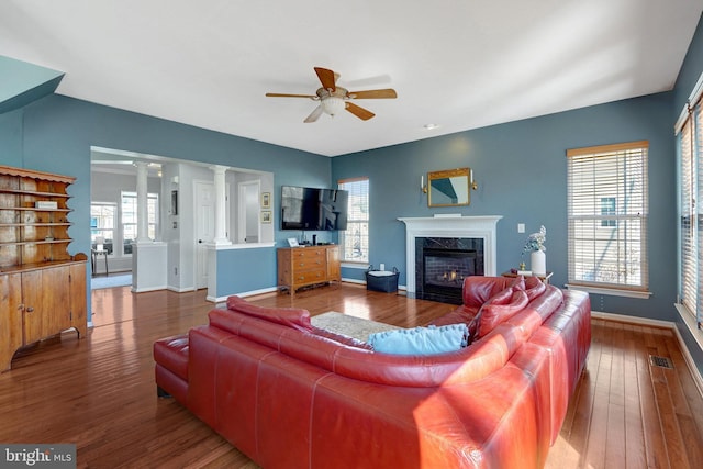 living area with a wealth of natural light, a high end fireplace, visible vents, and decorative columns