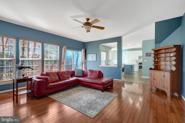 living area featuring ceiling fan, baseboards, and hardwood / wood-style flooring