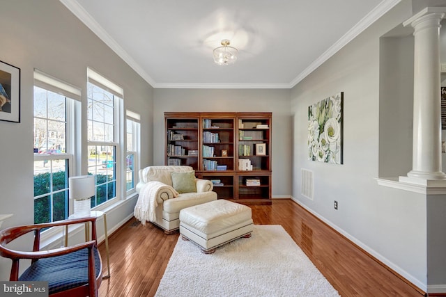 sitting room featuring decorative columns, baseboards, visible vents, wood finished floors, and crown molding