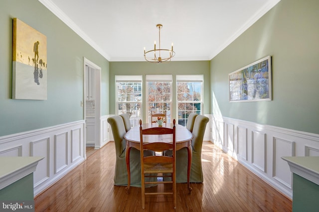 dining space featuring crown molding, light wood finished floors, and an inviting chandelier