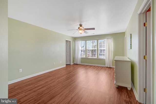 empty room with ceiling fan, baseboards, and wood finished floors