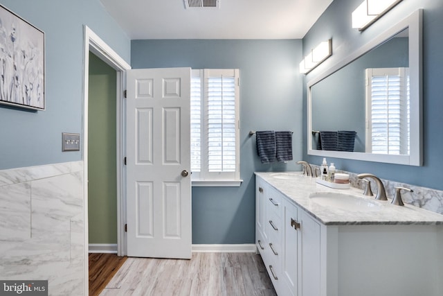 full bathroom with double vanity, wood finished floors, a sink, and visible vents