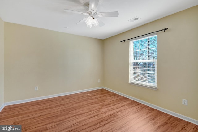 empty room featuring light wood-type flooring, baseboards, visible vents, and a ceiling fan