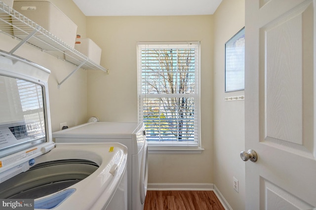 clothes washing area featuring washing machine and dryer, laundry area, dark wood finished floors, and baseboards