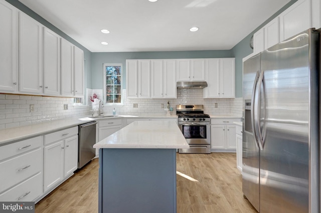 kitchen featuring a kitchen island, appliances with stainless steel finishes, light wood-type flooring, under cabinet range hood, and white cabinetry