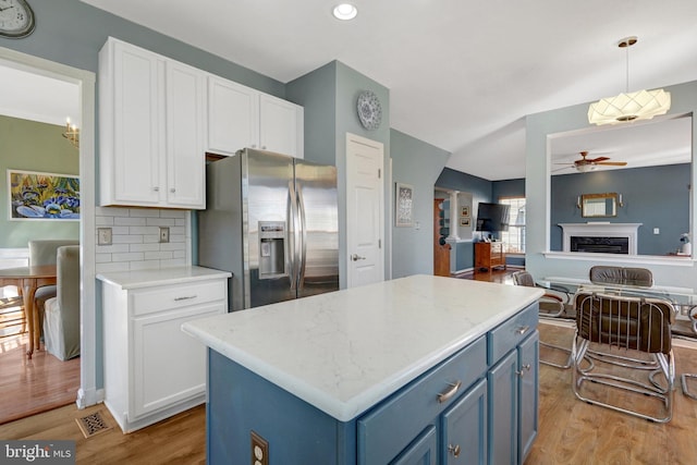 kitchen featuring stainless steel fridge, white cabinets, open floor plan, blue cabinets, and pendant lighting