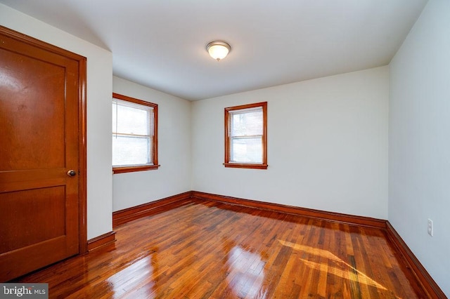 spare room featuring wood-type flooring and baseboards