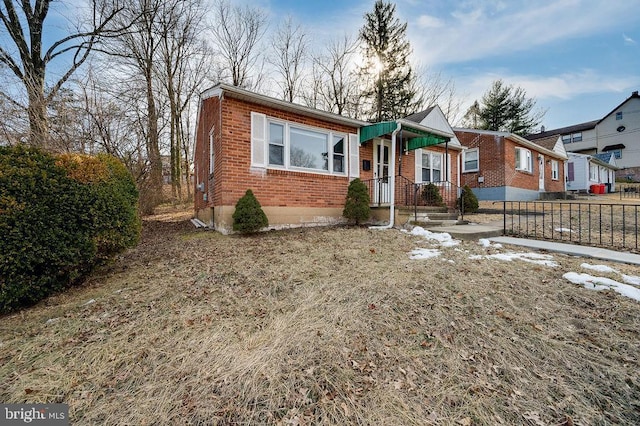 bungalow-style home featuring fence and brick siding