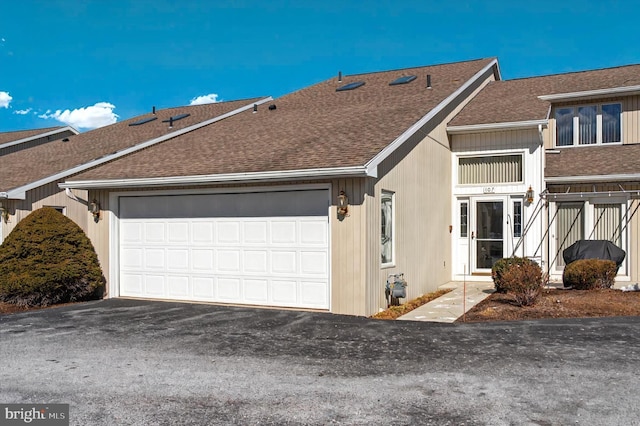 view of front facade with driveway, a garage, and roof with shingles