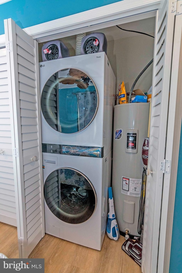 laundry room with wood finished floors, stacked washer and clothes dryer, water heater, and laundry area