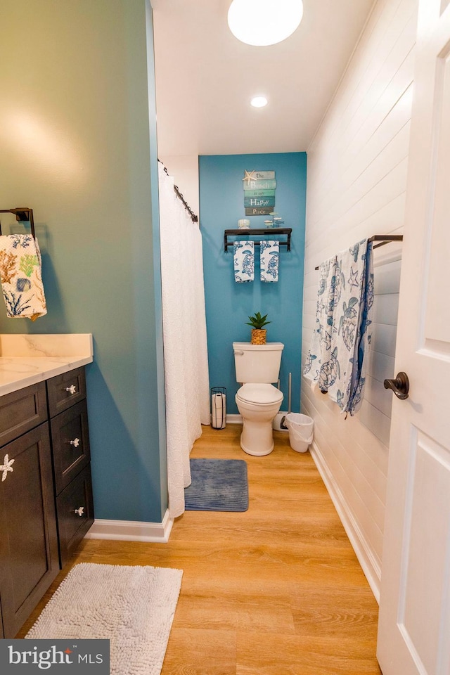 bathroom with toilet, baseboards, wood finished floors, and vanity