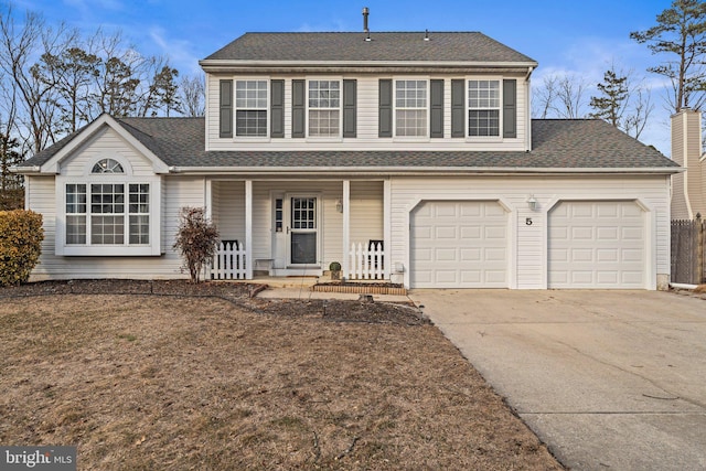 traditional home featuring a porch, roof with shingles, and driveway