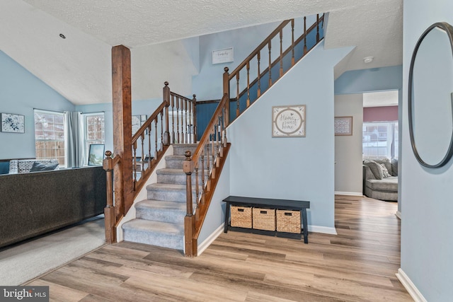 staircase with a wealth of natural light, baseboards, and wood finished floors