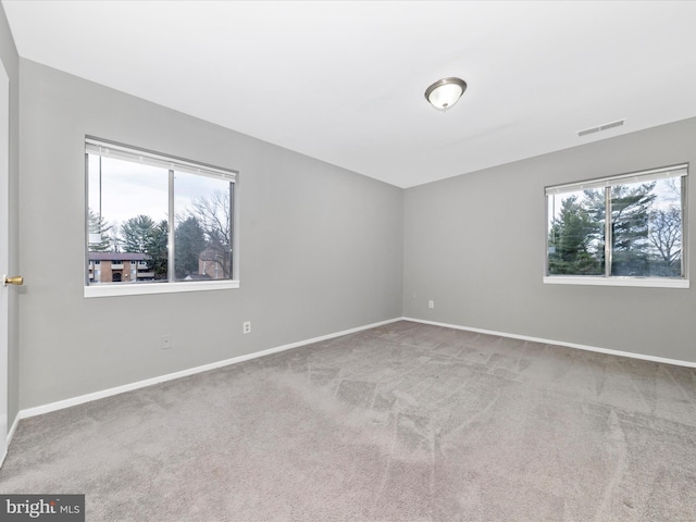 unfurnished room featuring plenty of natural light, carpet flooring, visible vents, and baseboards